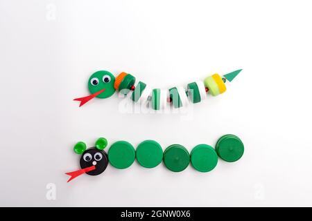 DIY summer craft for kids, how to make serpent, from plastic bottle cap, homemade handicraft, white background Stock Photo
