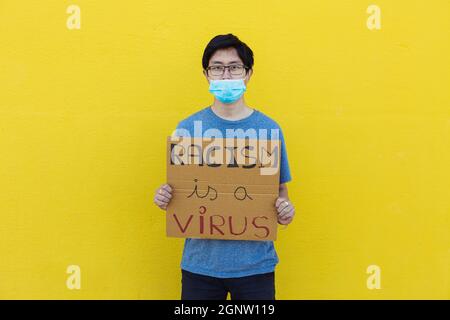 Chinese man wearing protective face mask holding a poster against asian racism  Stock Photo