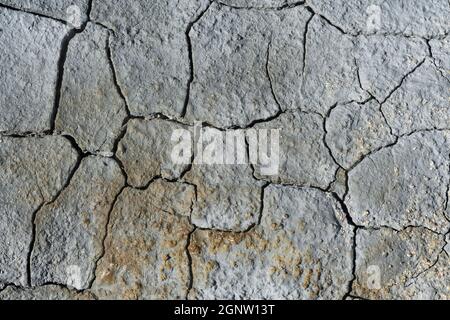 Gray light blue dry cracked surface of volcanic earth turned into desert. Natural background or texture taken in environment in crater of volcano Stock Photo