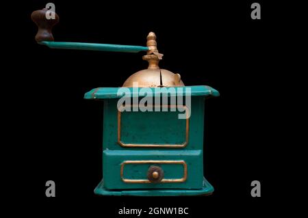 Old manual coffee grinder painted gold and green. Selective focus Stock Photo