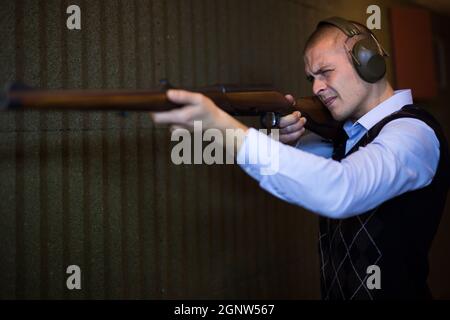 Concentrated man practicing shotgun shooting at firing range Stock Photo