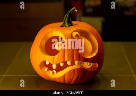 A jack-o-lantern isolated on the kitchen counter. Funny halloween pumpkin face. Stock Photo
