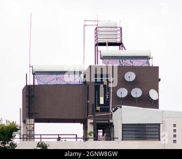 PVC water tank and solar tubular water heater panels along with storage tank installed on the terrace of a bungalow Stock Photo