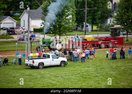 Onlookers gather between a white Chevrolet pickup truck and a tractor pull event at the Noble County Fairgrounds in Kendallville, Indiana, USA. Stock Photo