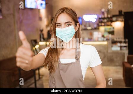 Waitress wearing a face mask at the coffee shop Stock Photo