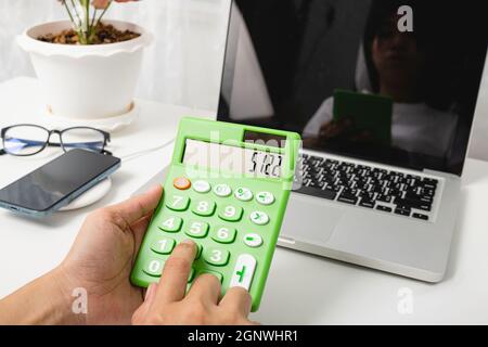Accountant working and analyzing financial calculating with calculator and laptop computer income-expenditure at office desktop, Business financial an Stock Photo