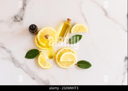 top view of slices of fresh lemon, lemon balm leaves and bright sun essential oil in glass bottles with a cork lid. natural organic cosmetic product Stock Photo