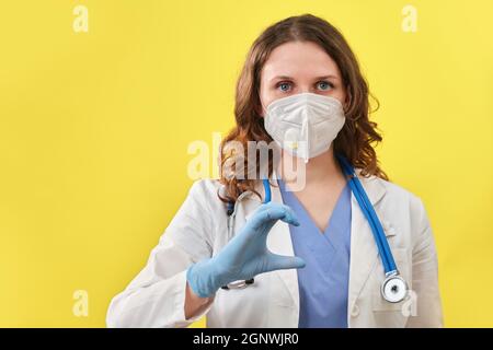 The medic shows the heart sign with his fingers, close-up. Doctor hand in medical glove with the sign of love for patients, concept Stock Photo