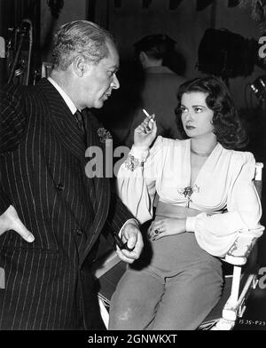 Executive Producer WALTER WANGER with his leading lady / wife JOAN BENNETT on set candid during filming of SECRET BEYOND THE DOOR 1947 director FRITZ LANG story Rufus King screenplay Silvia Richards music Miklos Rozsa gowns Travis Banton  Walter Wanger Productions (as a Diana Production) / Universal Pictures Stock Photo
