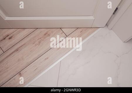 Aluminum threshold between ceramic tiles and parquet Stock Photo