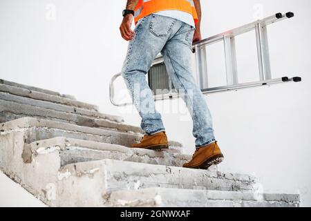 Professional builder carrying metal ladder, close up Stock Photo
