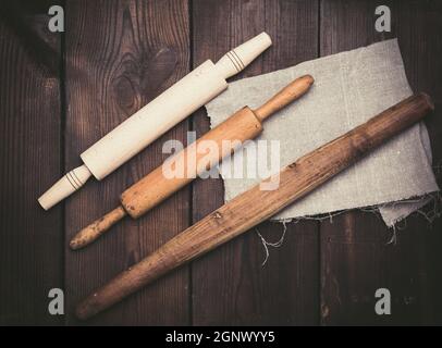 wooden rolling pins for rolling dough on a black background, new and very old utensils, top view Stock Photo