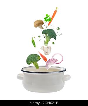 Fresh vegetables falling into a kitchen cooking casserole pot. Isolated on white background Stock Photo