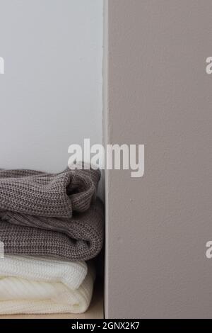 A stack of wool sweaters on the shelf. Grey and white sweater. Warm and cozy. Knitted clothing. Stock Photo