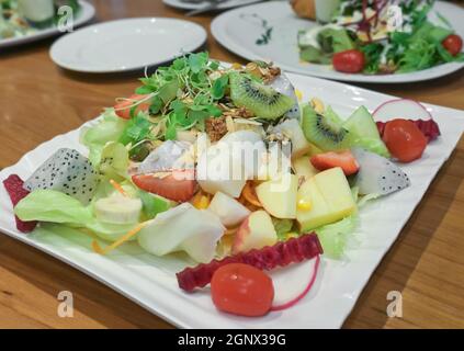 Fresh mix leaves salad with  lettuce, apple, cucumber, carrot, dragon fruit, kiwifruit, radish, tomato, sprouts, seeds and nuts. Healthy vegan and die Stock Photo