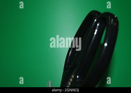 Closeup view of a stationery pot containing stationery items. stationery pot in front of a green background. Stock Photo