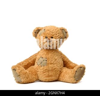 brown teddy bear sits on a white background, toy with patches Stock Photo