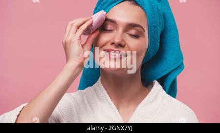 happy woman using silicone facial cleanser with closed eyes isolated on pink Stock Photo