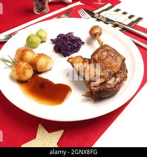 Roasted duck leg with bacon Brussels sprouts and red cabbage and dumplings on a white plate, holiday menu, Christmas dinner. Stock Photo