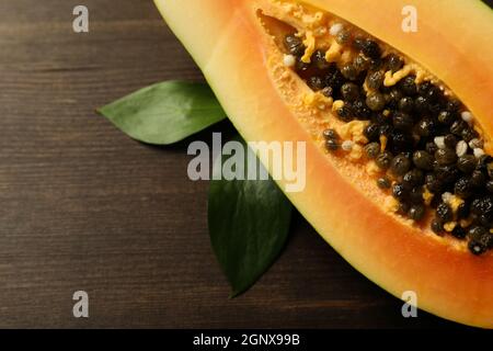 Half of papaya with leaves on wooden background Stock Photo