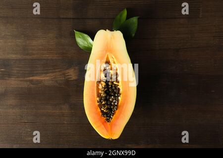 Half of papaya with leaves on wooden background Stock Photo