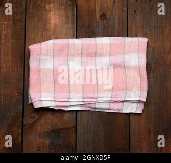 folded pink white kitchen towel on brown wooden background, top view Stock Photo