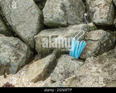 A light blue mouth and nose mask lying on boulders. Stock Photo