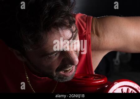 Sweaty athlete making physical exertion with weights Stock Photo