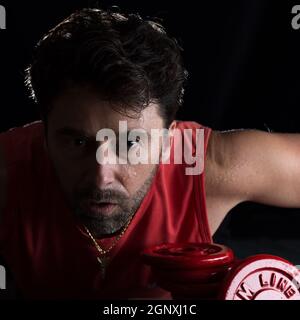 Sweaty athlete making physical exertion with weights Stock Photo