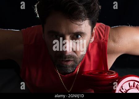 Sweaty athlete making physical exertion with weights Stock Photo