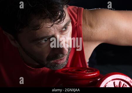 Sweaty athlete making physical exertion with weights Stock Photo