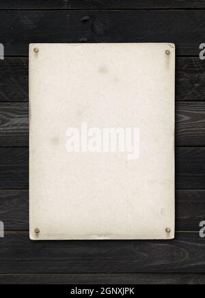 Old textured paper sheet nailed on a black wood table. vertical Mockup Stock Photo
