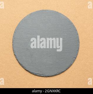 empty black round slate kitchen board on a brown background, top view Stock Photo