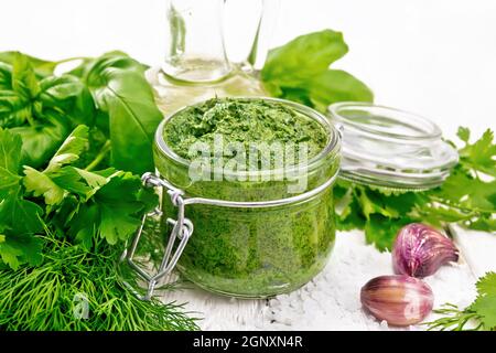 Sauce of dill, parsley, basil, cilantro, other spicy herbs, garlic and vegetable oil in a glass jar, coarse salt on wooden board background Stock Photo