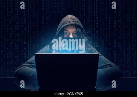 Hacking and malware concept. Hacker using laptop with binary code digital interface. Stock Photo