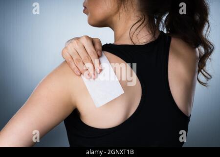 Woman Applying Stiff Shoulder Pain Patch After Injury Stock Photo