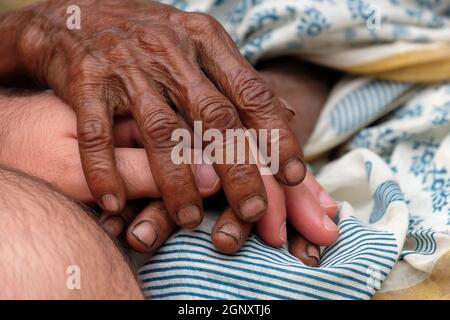 Hands, young and old, on top of each other, comforting each other, Kumrokhali, West Bengal, India Stock Photo