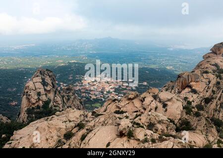 View from above, drone point of view, stunning aerial landscape with a granite mountain in the foreground and San Pantaleo village in the distance. Stock Photo