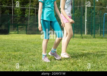 Children are dancing on the lawn. The girls are filming and dancing. Jumping girls on a hot day. Children are having fun. Shooting without faces. Stock Photo