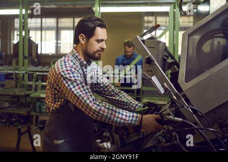 Young worker using special industrial press while making new footwear at shoe factory Stock Photo