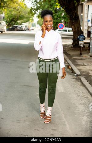 beautiful african young woman walking in the street and talking on mobile phone smiling Stock Photo