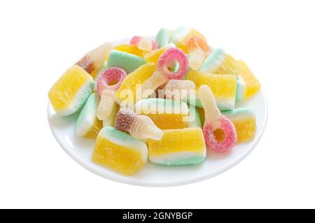 Sweet jelly candies in the form of fruit slices, bottles, loops in sugar on a plate isolated on a white background. Close-up Stock Photo