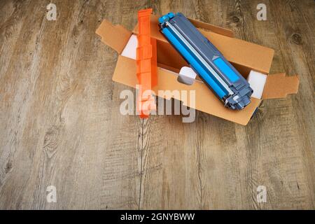 Unboxing of toner cartridge for a color laser printer on wooden background Stock Photo