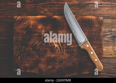 Knife over rustic wooden cutting board Stock Photo