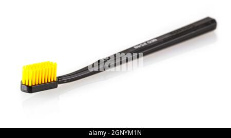 black toothbrush with yellow bristles isolated on white. Selective focus Stock Photo