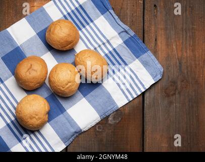 baked round small buns on a brown wooden table, top view Stock Photo