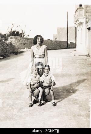 RAF Service family pose outside thier married quarter, Valletta, Malta. 1959. Archive. Old sepia photograph. Stock Photo