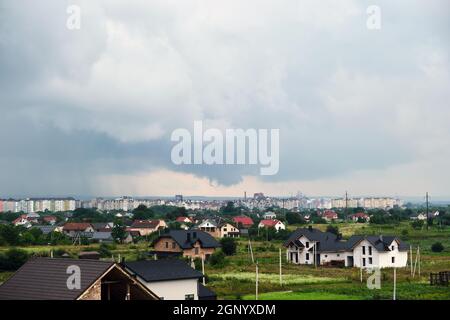 Landscape of dark clouds forming on stormy sky during thunderstorm over city rural area. Stock Photo