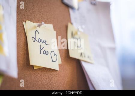 Close up of pinned note “Love you” on cork board Stock Photo