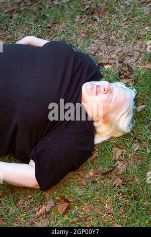 Obese woman lying unconscious on the ground outdoors Stock Photo